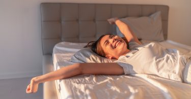 happy young woman stretching on mattress