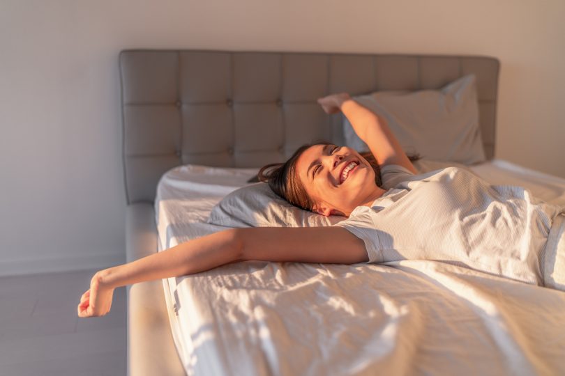 happy young woman stretching on mattress