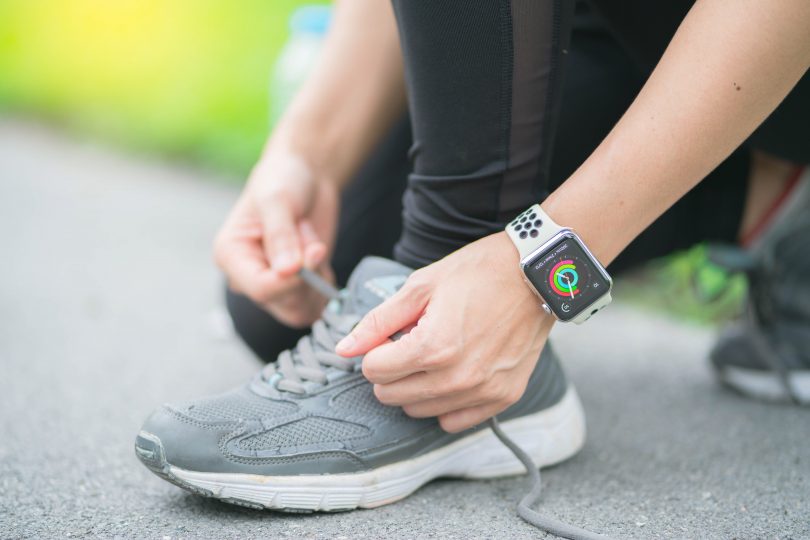 person tying shoes while wearing apple watch outside