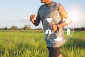 runner passing through grassy field with smartwatch