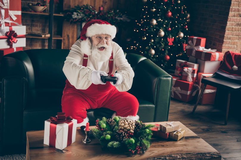 Santa sitting on the couch and playing video games