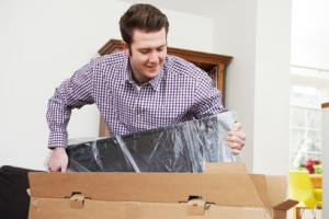 man taking a new tv out of a cardboard box