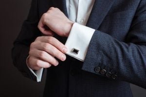 man admiring cuff links on his sleeves