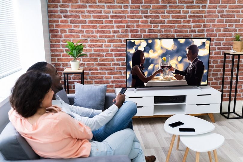 Rear view of a couple watching movie on television at home