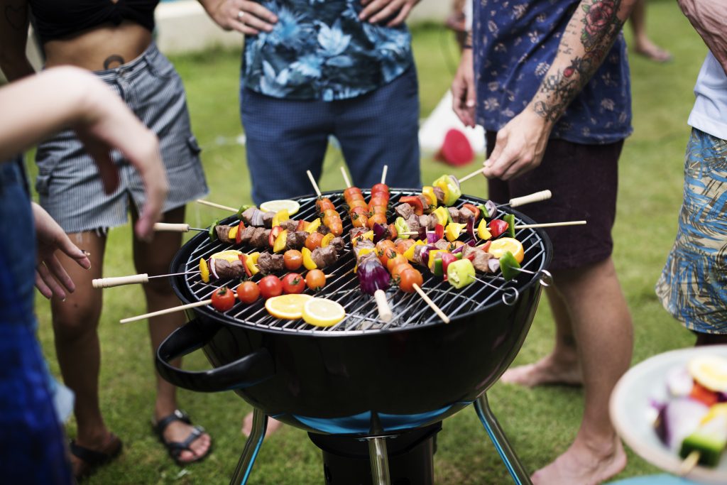 group of friend around a charcoal grill cooking food together