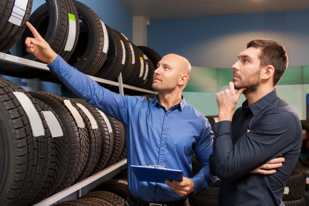 tire salesman explaining different types of tires to customer
