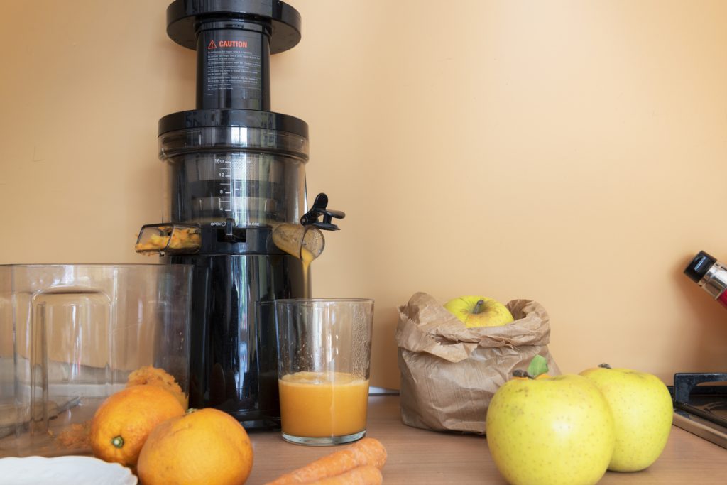 juicer making juice out of apples carrots and oranges 