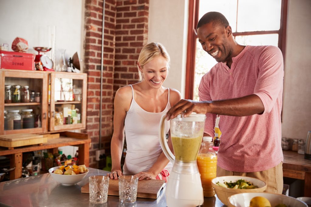 male and female using a blender in kitchen