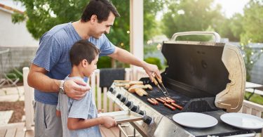 father teaching son how to grill