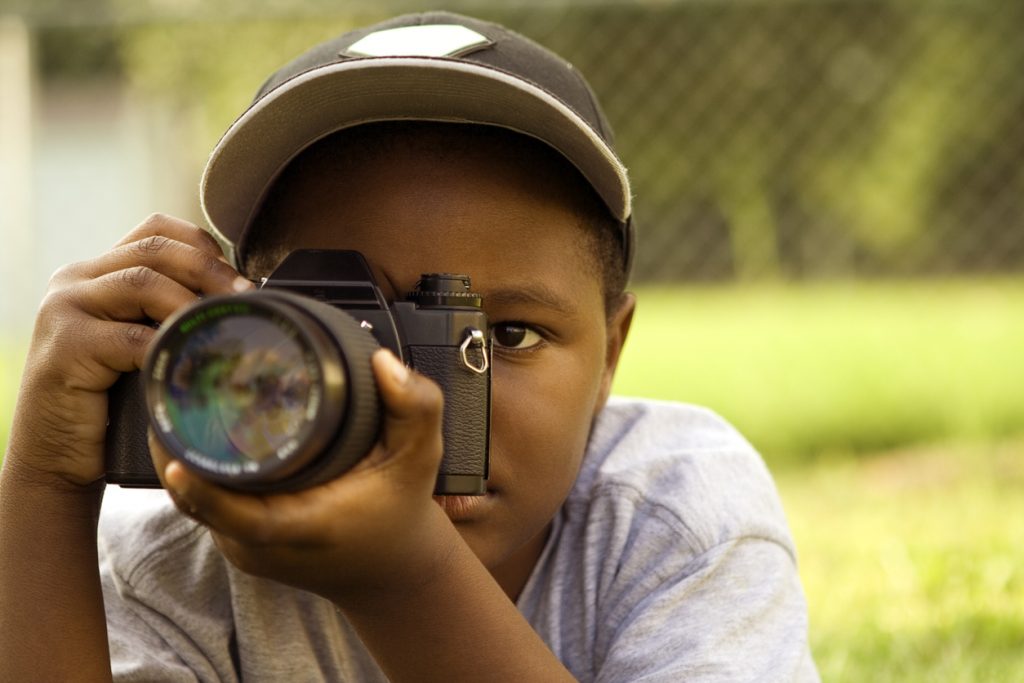 young boy taking a photo outside with DSLR camera