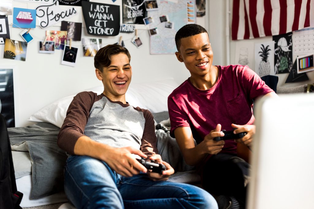 2 happy teenagers playing video games at home