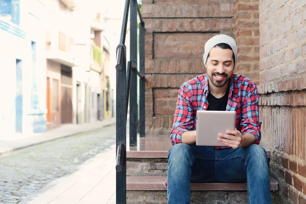 young happy guy using tablet outside