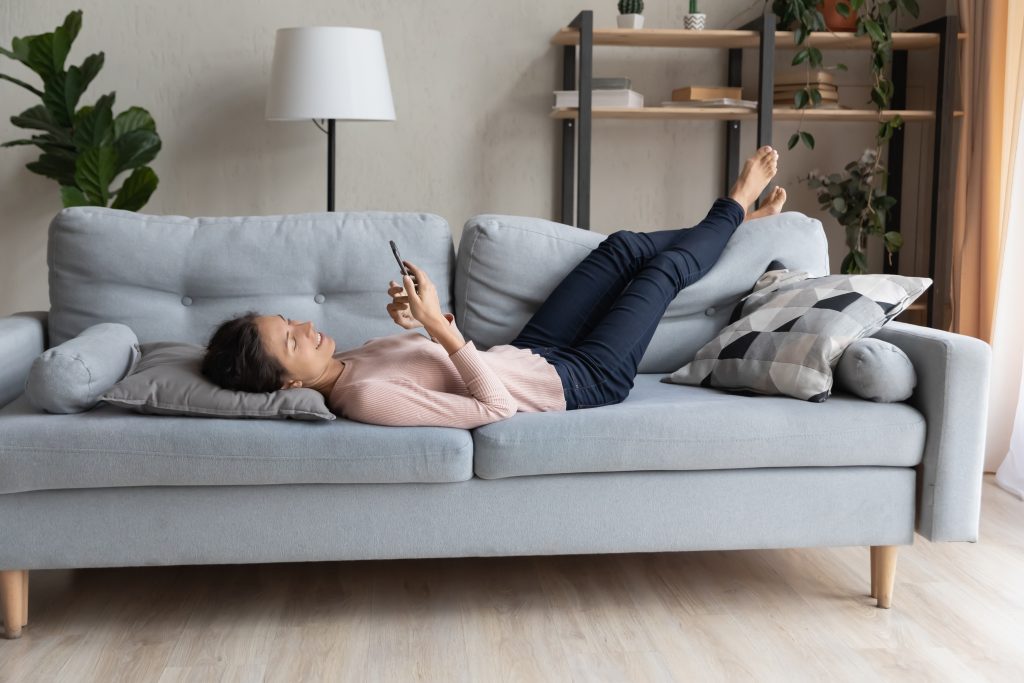 woman relaxing on the couch while browsing phone