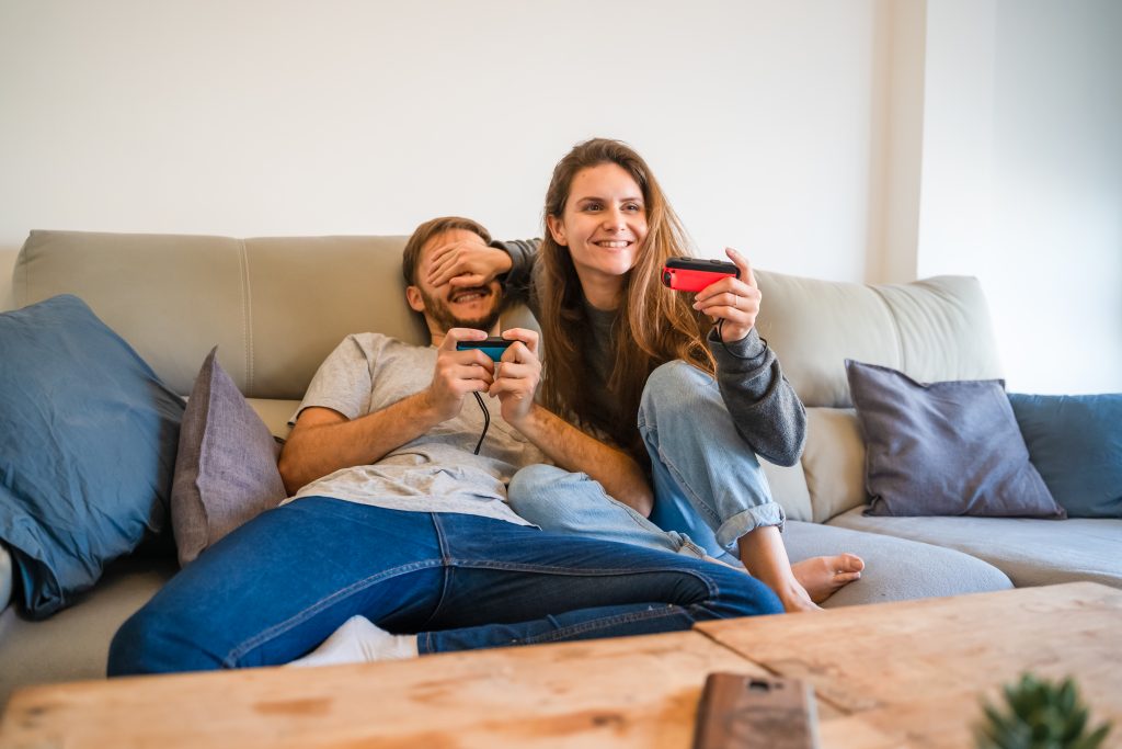 happy couple playing Nintendo Switch on couch at home