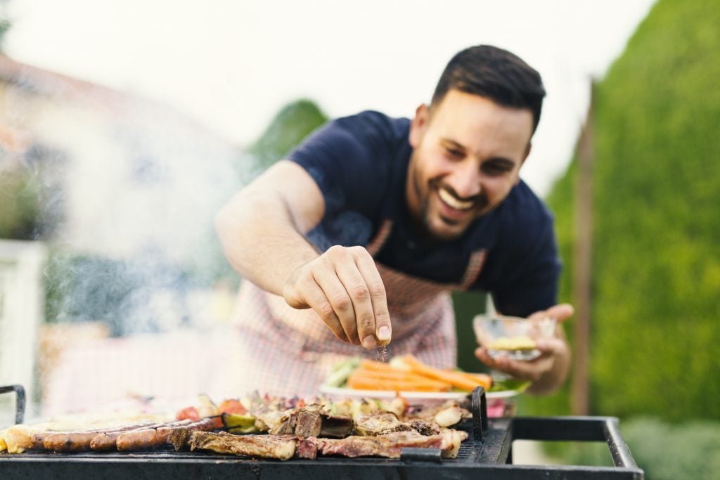 Man seasoning food while having fun grilling