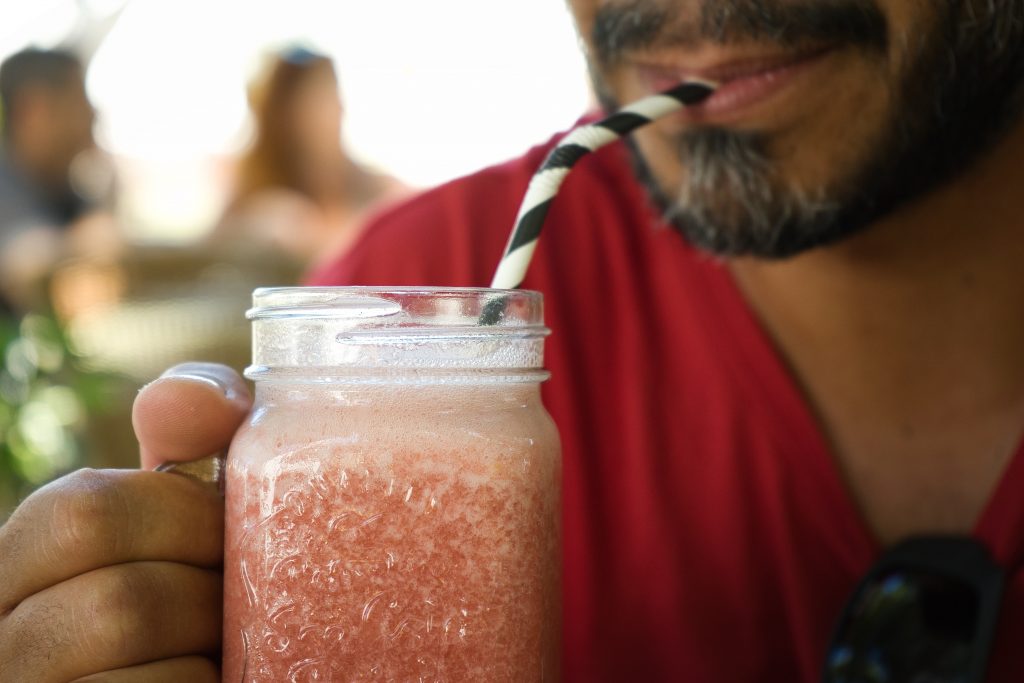 Bearded man sipping cold drink through striped straw