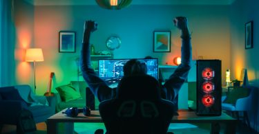 Young man in gaming chair with arms raised victoriously
