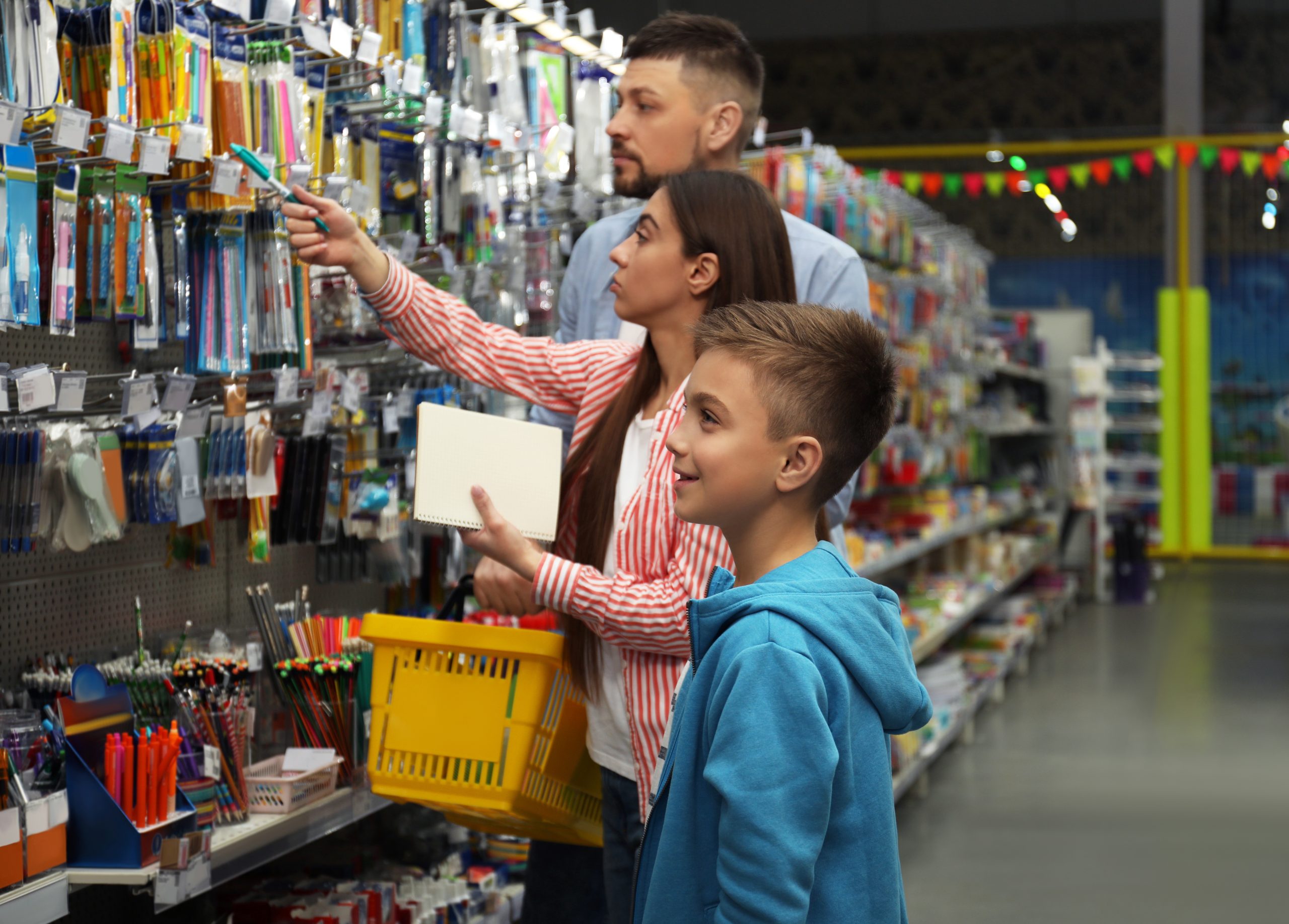 Young hispanic parents and son shopping for school supplies