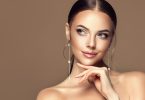 Closeup of beautiful young woman with slicked hair and bare shoulders wearing beautiful long dangle earrings