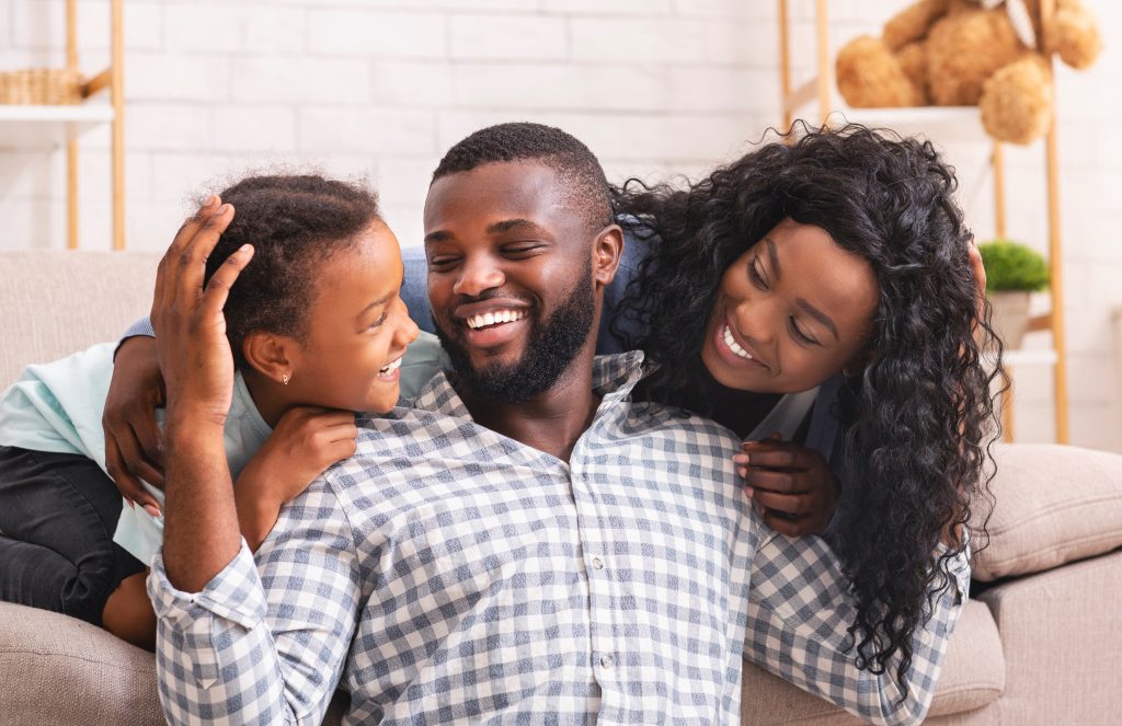 Black mom and dad, smiling at young daughter