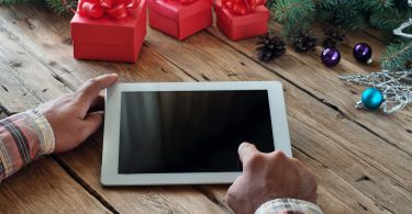 Hands pointing to SmartHome tablet next to 3 red gift boxes