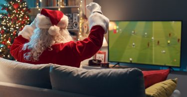 Santa on sofa cheering on football game on TV
