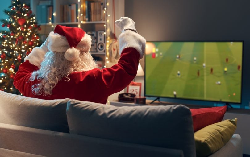 Santa on sofa cheering on football game on TV