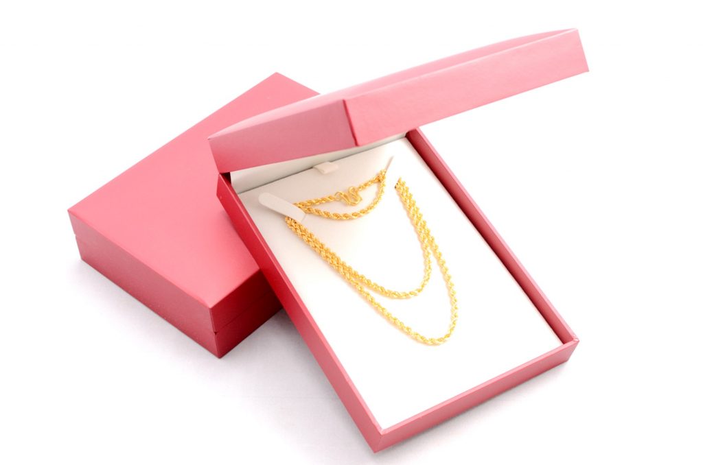 A gold necklace in a red jewelry box is set for Valentine's Day gifts with a white-themed background.